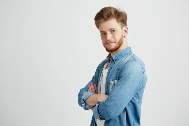 Retrato de homem bonito jovem confiante, sorrindo com braços cruzados.