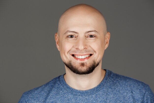 Retrato de homem bonito na camisa cinza, sorrindo para a câmera sobre a parede escura