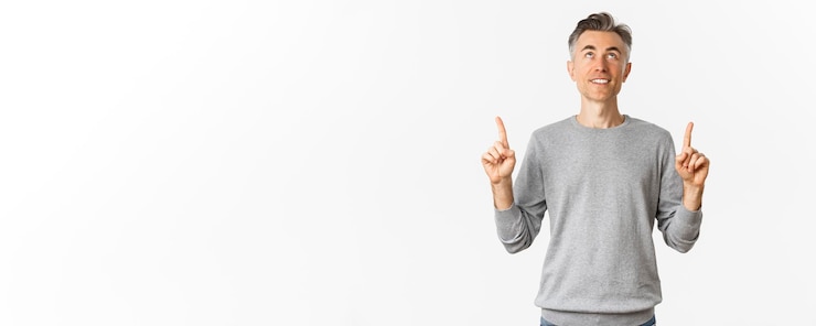 Foto grátis retrato de homem bonito sorridente com cabelo curto olhando e apontando os dedos para algo interessante lendo um anúncio em pé sobre fundo branco