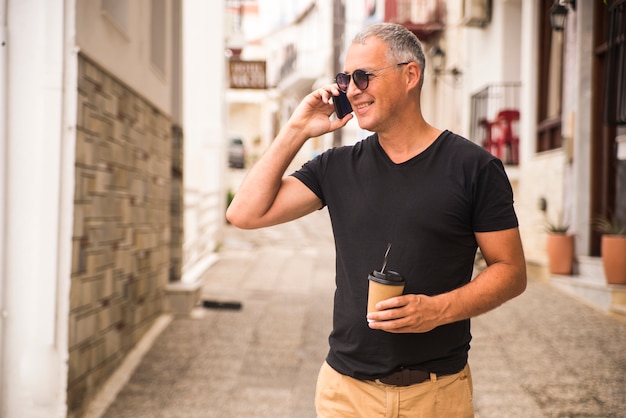 Retrato de homem bonito tomando cafe e conversando falando no telefone