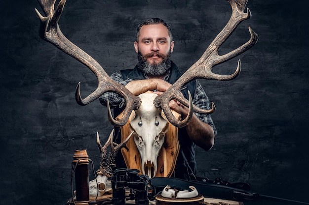 Retrato de homem caçador detém o crânio de um veado.