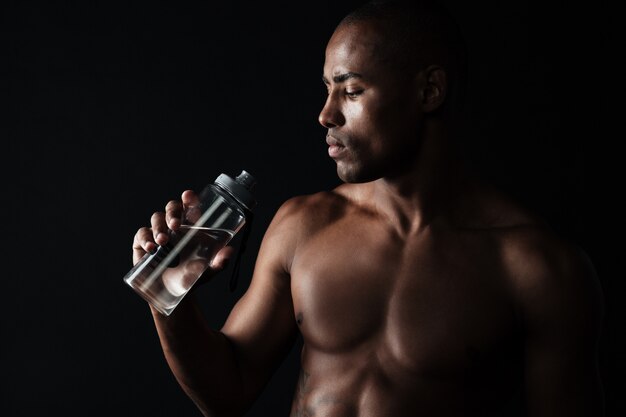 Retrato de homem cansado de esportes afro-americanos jovens, segurando a garrafa de água