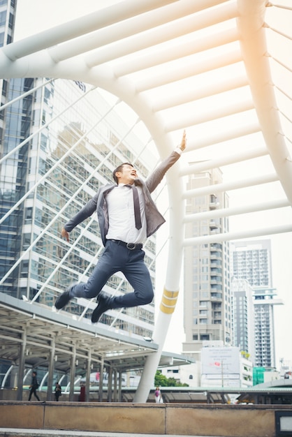 Retrato de homem de negócios atraente comemora saltando levanta o punho no alto ao ar livre.