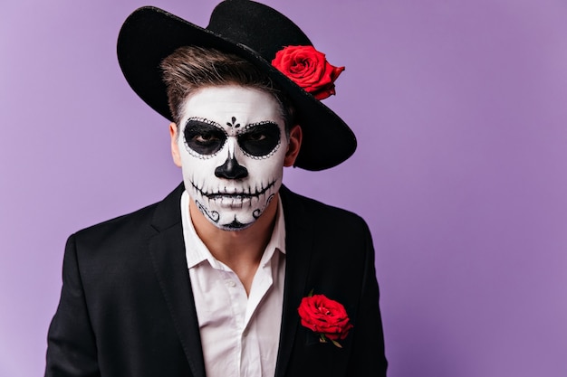 Retrato de homem em assustadora máscara de estilo mexicano, olhando severamente para a câmera.