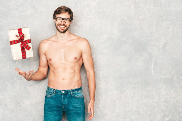 Retrato de homem forte bonito desportivo. Modelo de aptidão atlética saudável posando perto de uma parede cinza em jeans.