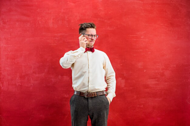 Retrato de homem intrigado, falando por telefone no vermelho