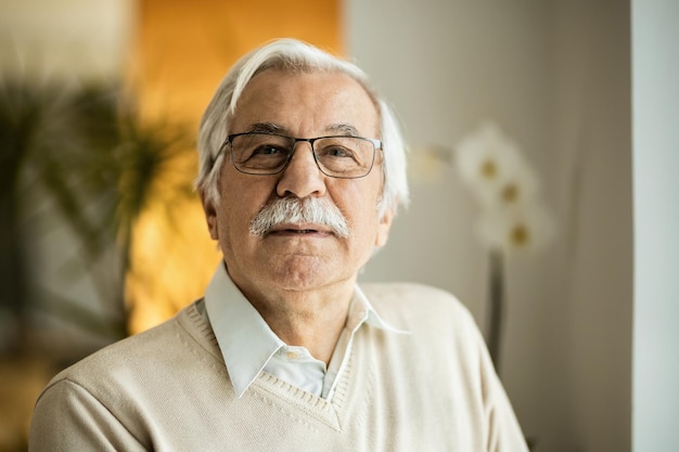 Retrato de homem maduro com cabelo branco e bigode olhando para a câmera