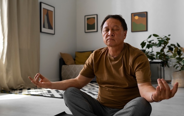 Foto grátis retrato de homem mais velho meditando em casa