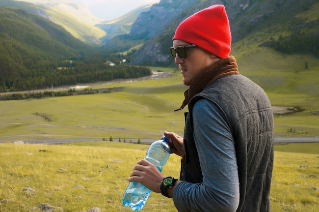 Retrato de homem moderno viajando pelas montanhas, use chapéu vermelho e roupas modernas, tire fotos