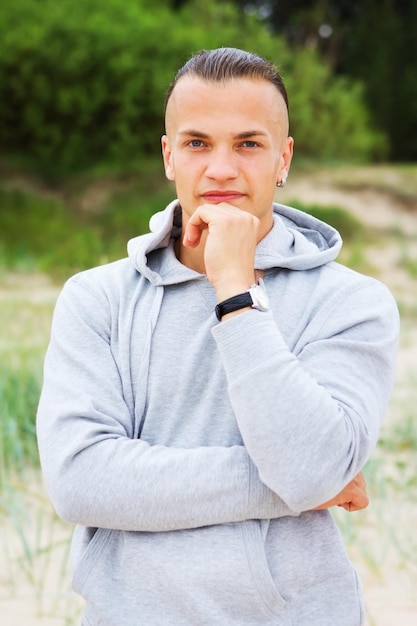 Retrato de homem posando na praia com um casaco