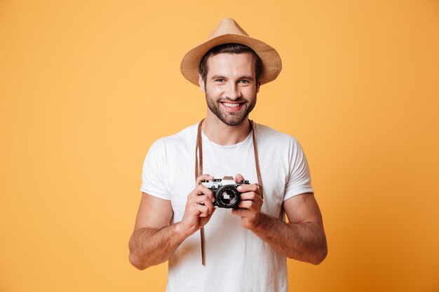 Retrato de homem positivo com câmera retro em pé isolado