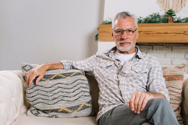 Foto grátis retrato, de, homem sênior, óculos desgastando, sentar sofá