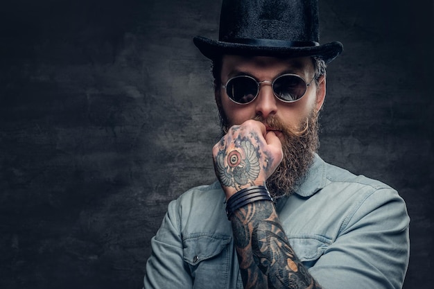 Foto grátis retrato de homem sério e barbudo em óculos escuros e chapéu de cilindro.