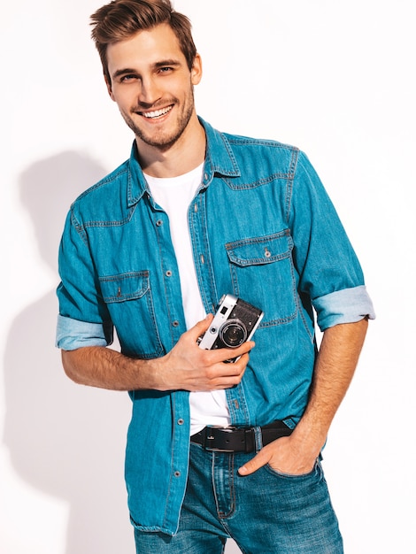 Foto grátis retrato de homem sorridente bonito vestindo roupas jeans de verão. modelo masculino tirando foto na câmera fotográfica vintage velha.