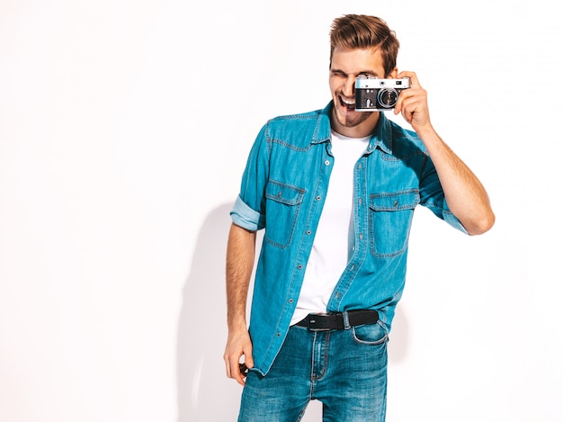 Retrato de homem sorridente bonito vestindo roupas jeans de verão. modelo masculino tirando foto na câmera fotográfica vintage velha.