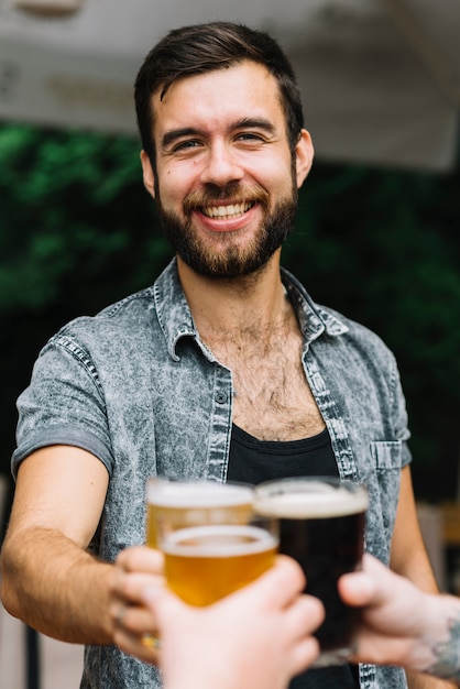 Foto grátis retrato, de, homem sorridente, brindar, copos cerveja, óculos, com, seu, amigo