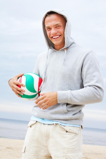 Retrato de homem sorridente na praia com bola