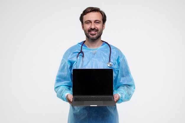 Retrato de homem vestindo bata médica e segurando laptop