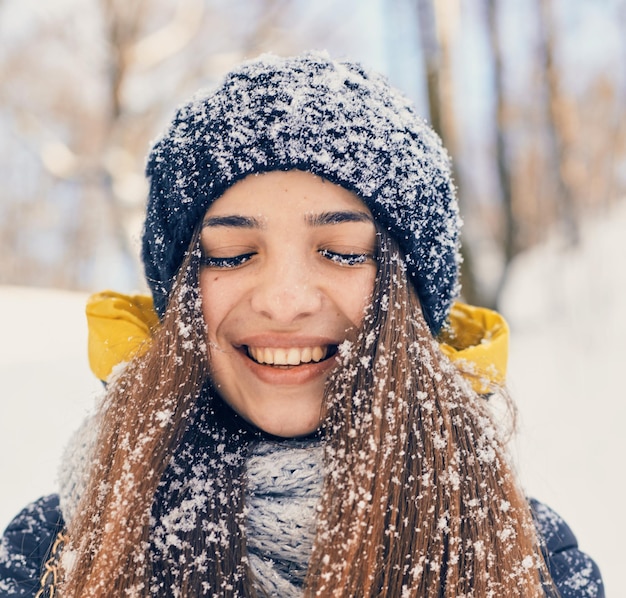 Retrato de inverno da bela jovem vestindo malha coberta de neve. nevando o conceito de moda de beleza de inverno.