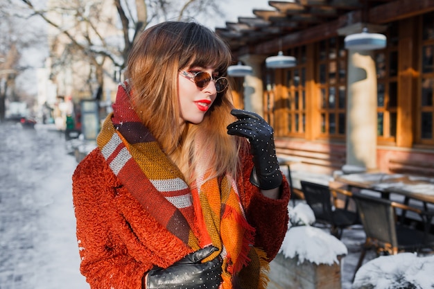 Retrato de inverno elegante mulher morena com óculos retrô posando ao ar livre