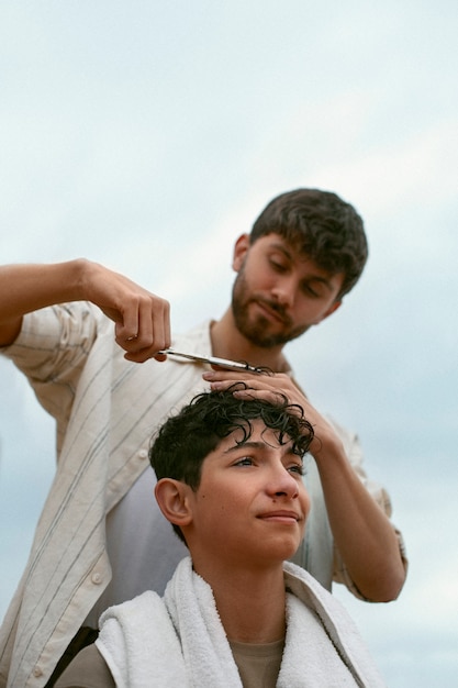 Retrato de irmãos ao ar livre durante uma sessão de corte de cabelo