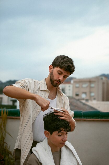 Retrato de irmãos ao ar livre durante uma sessão de corte de cabelo