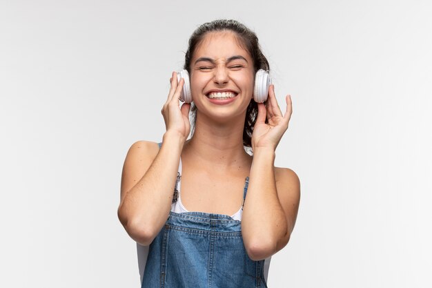 Retrato de jovem adolescente de macacão ouvindo música em fones de ouvido