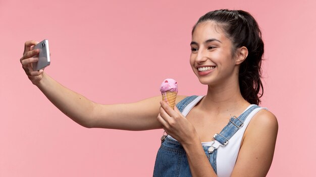 Retrato de jovem adolescente tirando uma selfie enquanto segura um sorvete