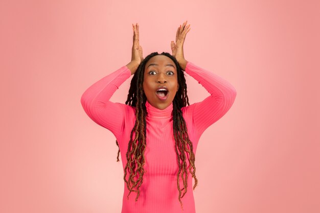 Retrato de jovem afro-americano isolado em fundo rosa.