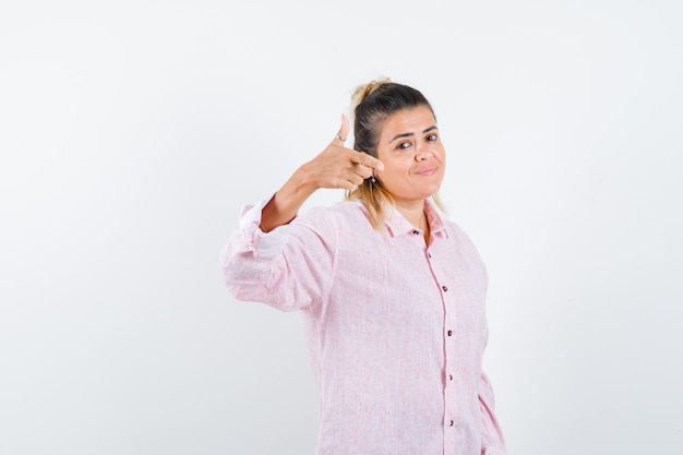 Retrato de jovem apontando para a câmera com uma camisa rosa e uma visão frontal confiante