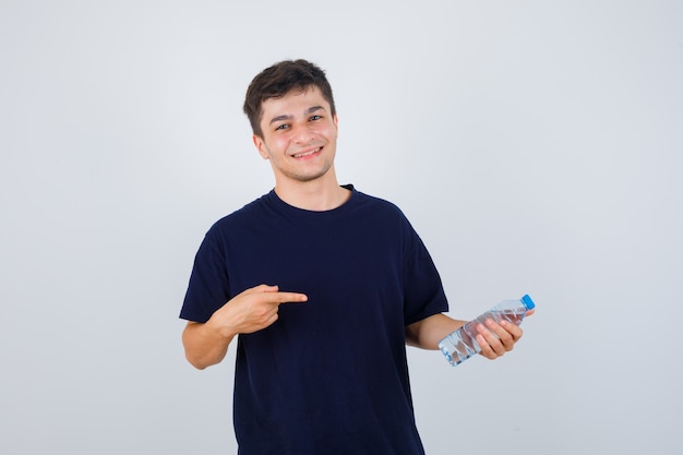 Retrato de jovem apontando para uma garrafa de água em uma camiseta preta e olhando confiante para a frente