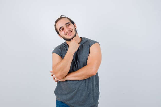 Retrato de jovem apto masculino em pose pensativa com capuz sem mangas e vista frontal alegre