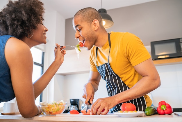 Retrato de jovem casal latino cozinhando juntos na cozinha de casa