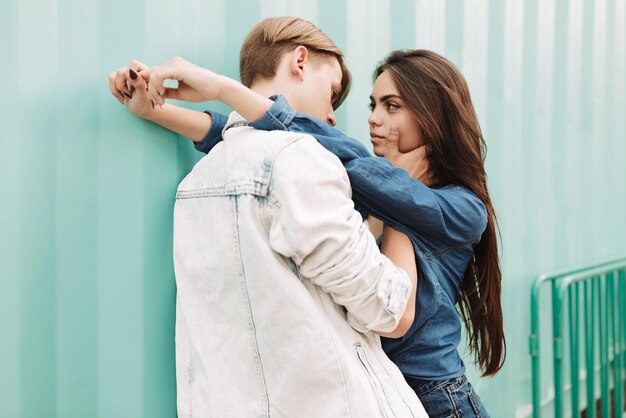 Retrato de jovem casal lindo abraçando uns aos outros em pé sobre fundo azul. senhora bonita sonhadoramente olhando para o namorado