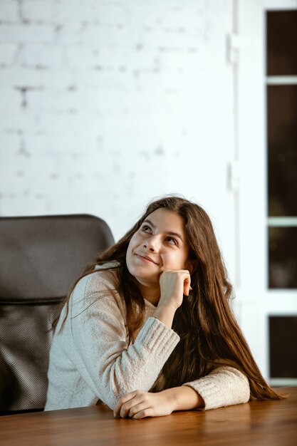 Retrato de jovem caucasiana em roupas casuais parece sonhador, fofo e feliz