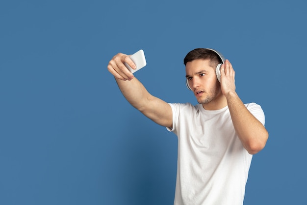 Foto grátis retrato de jovem caucasiano sobre fundo azul do estúdio.