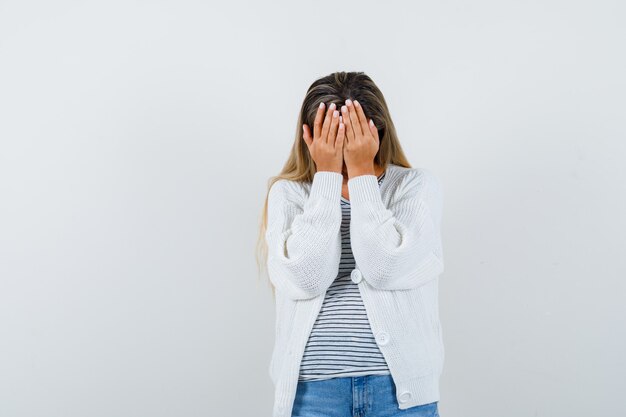 Retrato de jovem com as mãos na cabeça em t-shirt, jaqueta e vista frontal deprimida