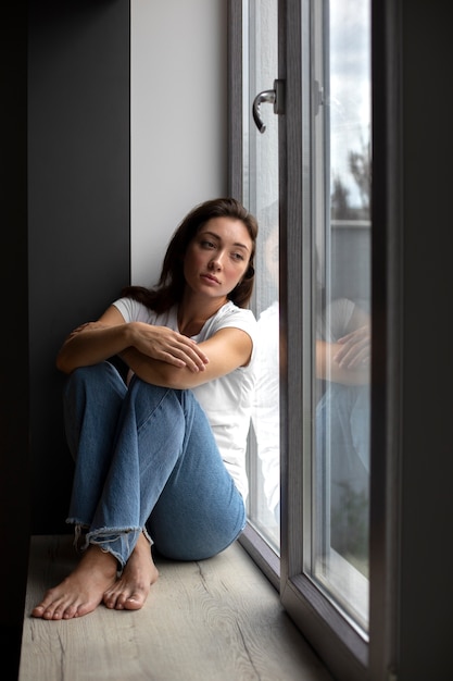 Foto grátis retrato de jovem com baixa auto-estima sentado perto da janela em casa