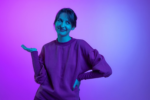 Retrato de jovem com capuz posando isolado sobre fundo roxo gradiente rosa na luz neon