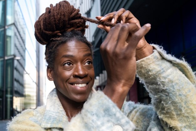 Foto grátis retrato de jovem com dreadlocks afro posando enquanto na cidade