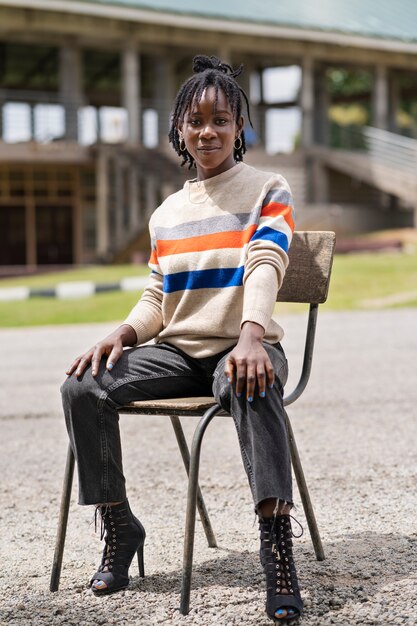 Retrato de jovem com dreadlocks afro sentado na cadeira ao ar livre