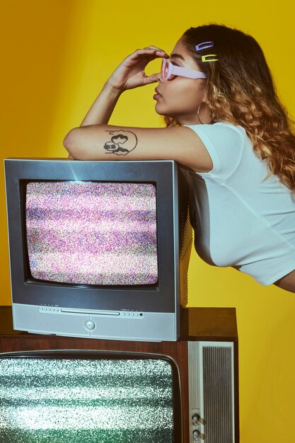 Retrato de jovem com estilo de moda dos anos 2000 posando com tv