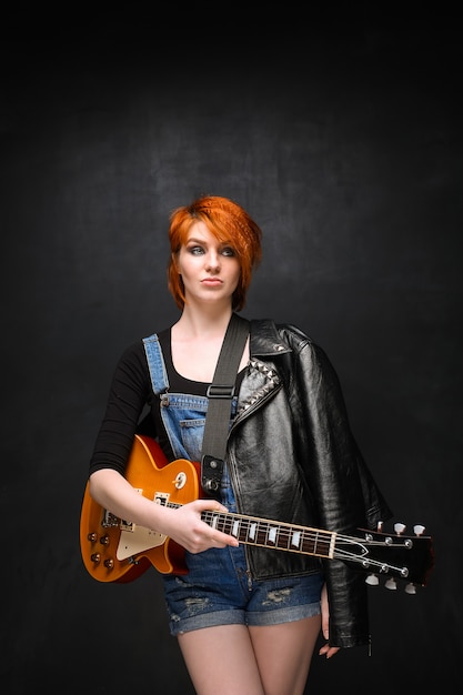 Foto grátis retrato de jovem com guitarra sobre fundo preto.