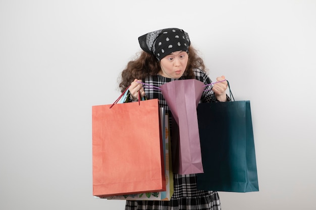 Retrato de jovem com síndrome de down, olhando para o monte da sacola de compras.