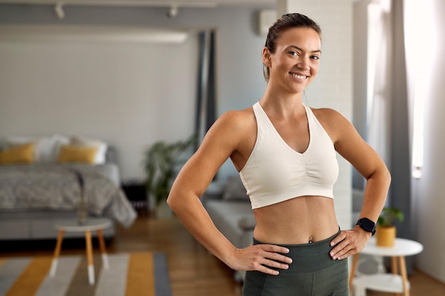 Retrato de jovem desportista feliz em pé na sala de estar e olhando para a câmera