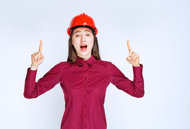 Retrato de jovem em capacete apontando para cima.