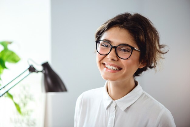 Retrato de jovem empresária linda sorrindo no local de trabalho no escritório.