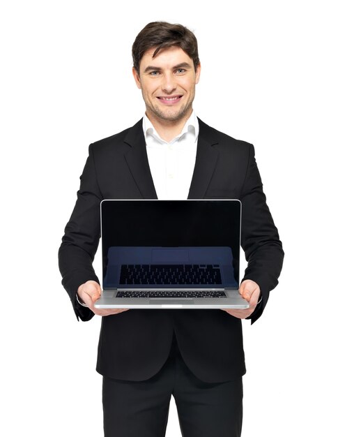 Retrato de jovem empresário feliz mantém o laptop com tela preta em branco, isolada no branco.