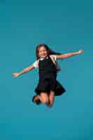 Foto grátis retrato de jovem estudante em uniforme escolar pulando no ar