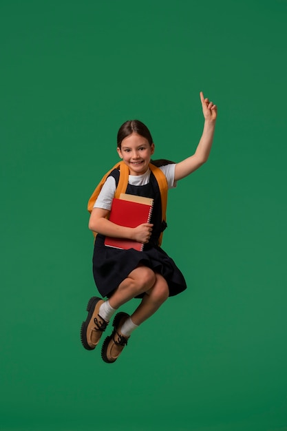 Retrato de jovem estudante em uniforme escolar pulando no ar